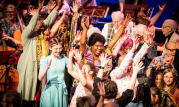 Diverse group of people with hands raised smiling