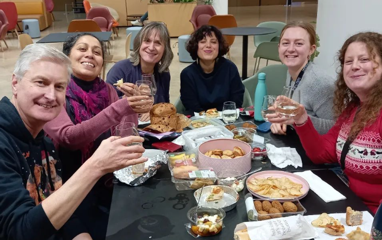 Group of people seated at a lunch table smiling to camera