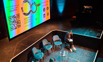 A stage with a large projector showing an ABO slide