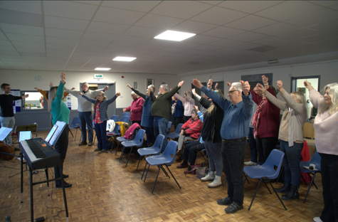 Group of people in a room standing with hands raised