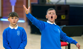 Young boy sings passionately with hands raised