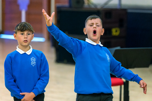 Young boy sings passionately with hands raised