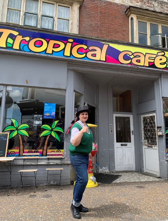 Woman stands outside Tropical Cafe smiling