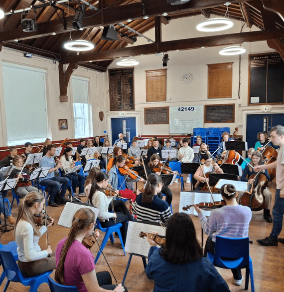 A large group of young musicians rehearsing in a hall