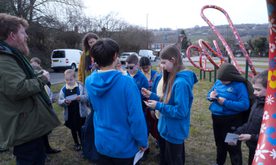 A group of students gather round the dancing flowers of Doe Lea sculpture