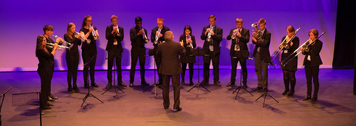 A row of brass players performing on a stage.