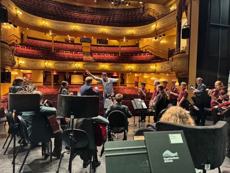 A group of students and musicians rehearsing on stage