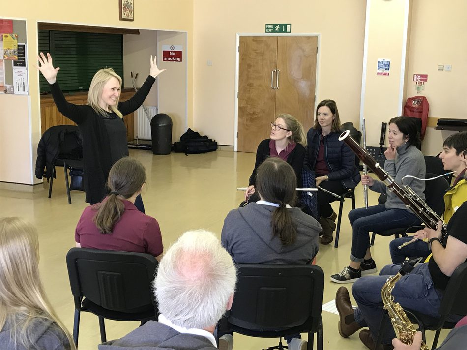A woman leading a workshop with a group of musicians.