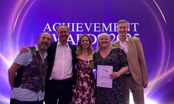 A group of people smile holding an award certificate