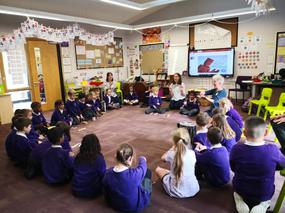 Group of primary school students sat in circle on the floor