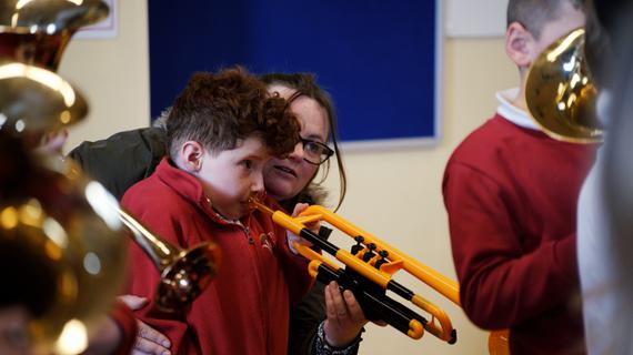 Teacher supporting young student to play instrument
