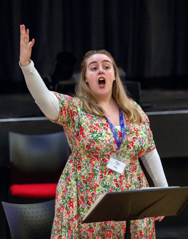 Chloe singing with arm raised in the air