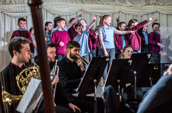 Primary school students sing and point on stage