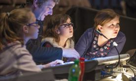 Three girls sit with a man at a sound desk.