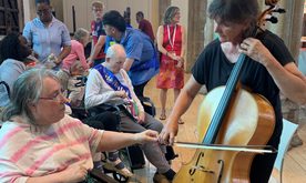 A musician playing an instrument, a woman in a wheelchair watches