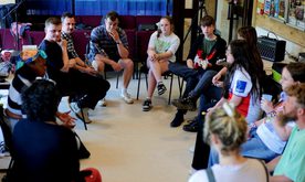 A group of young people in a music workshop seated in a circle