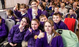 Group of students smiling with thumbs up looking into camera