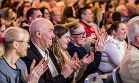 Audience members smiling and clapping together